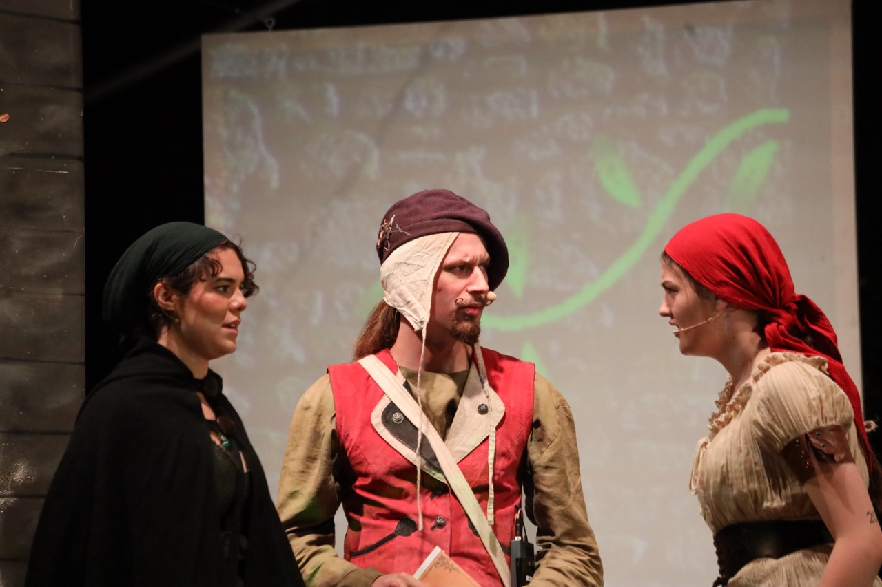 Drei Schauspielende diskutieren auf der Bühne.